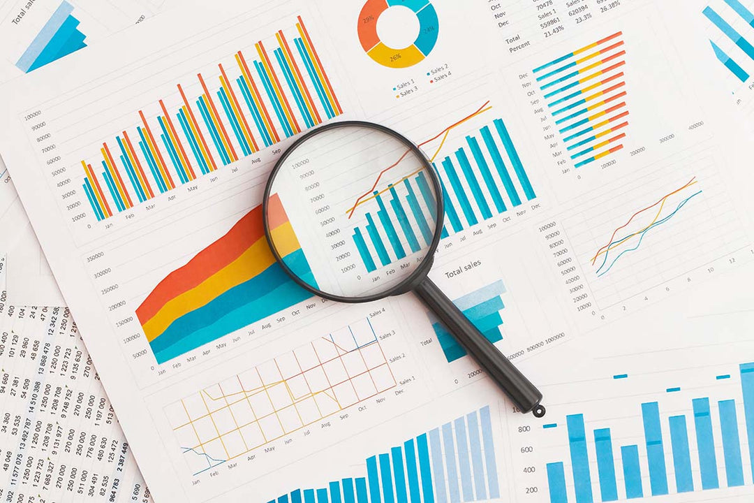 stock photo of papers showing graphs and charts with a magnifying glass laying on top