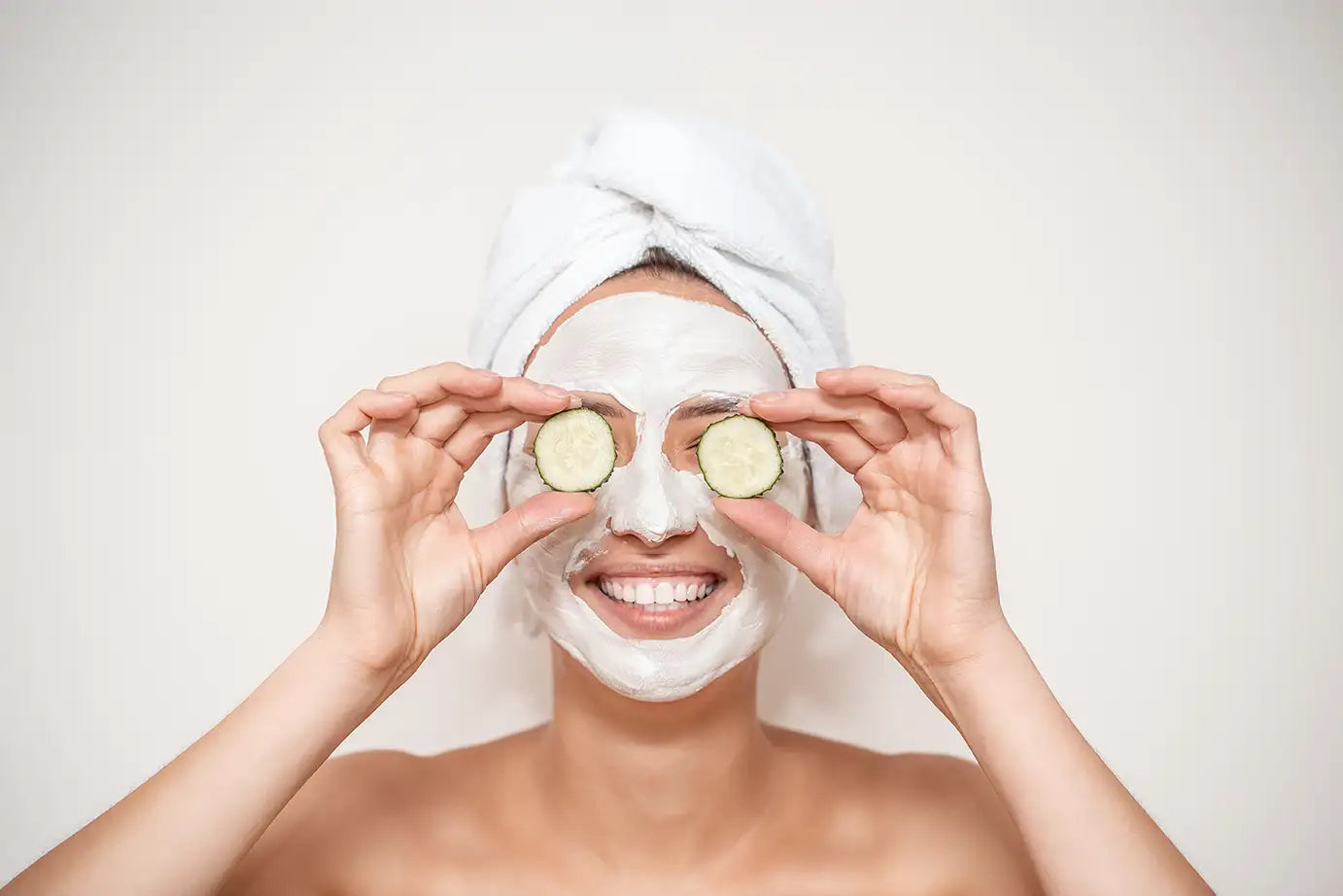 stock image of a person wearing a yogurt facemask and covering eyes with cucumbers